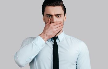 Embarrassed man covering his mouth with his hand