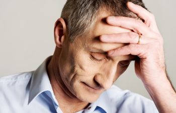 Depressed elderly man with his hand placed on his forehead after receiving cancer diagnosis