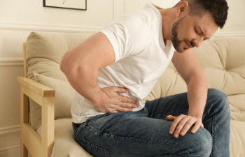 man suffering from pain in lower right abdomen on sofa at home